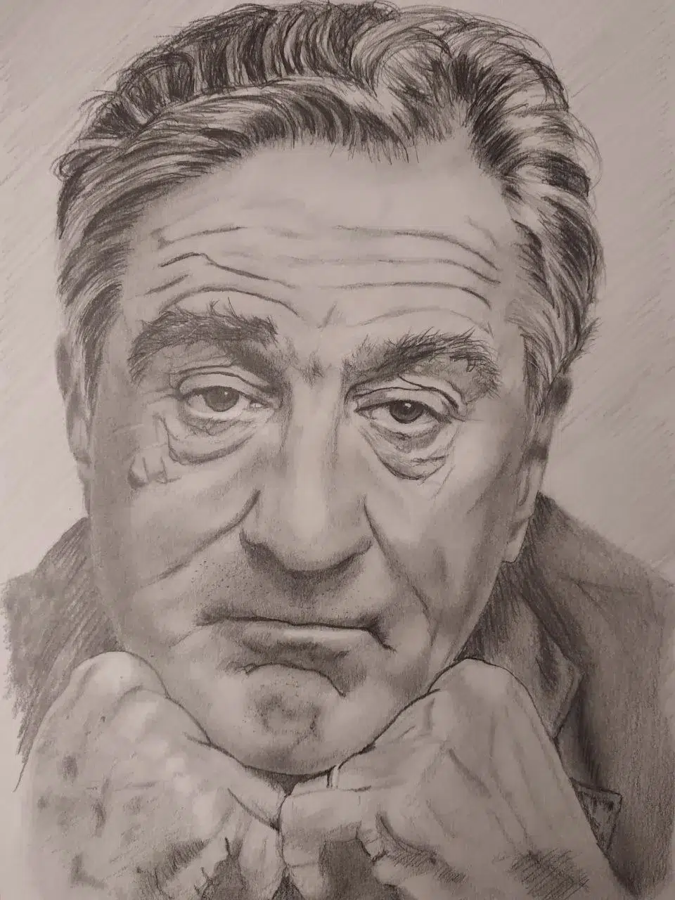 Retrato a lápiz del actor Robert De Niro apoyando el mentón sobre sus manos con mirada intensa